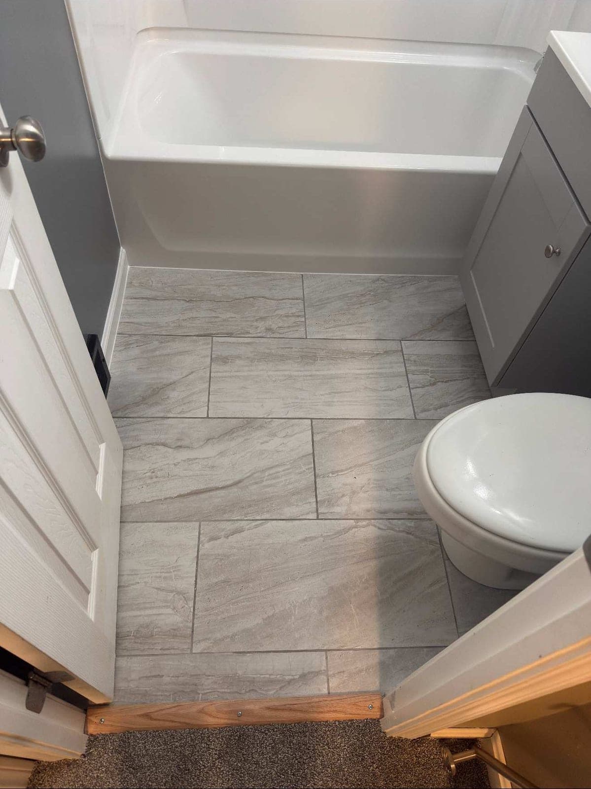 New large-format gray tile floor beside a new tub