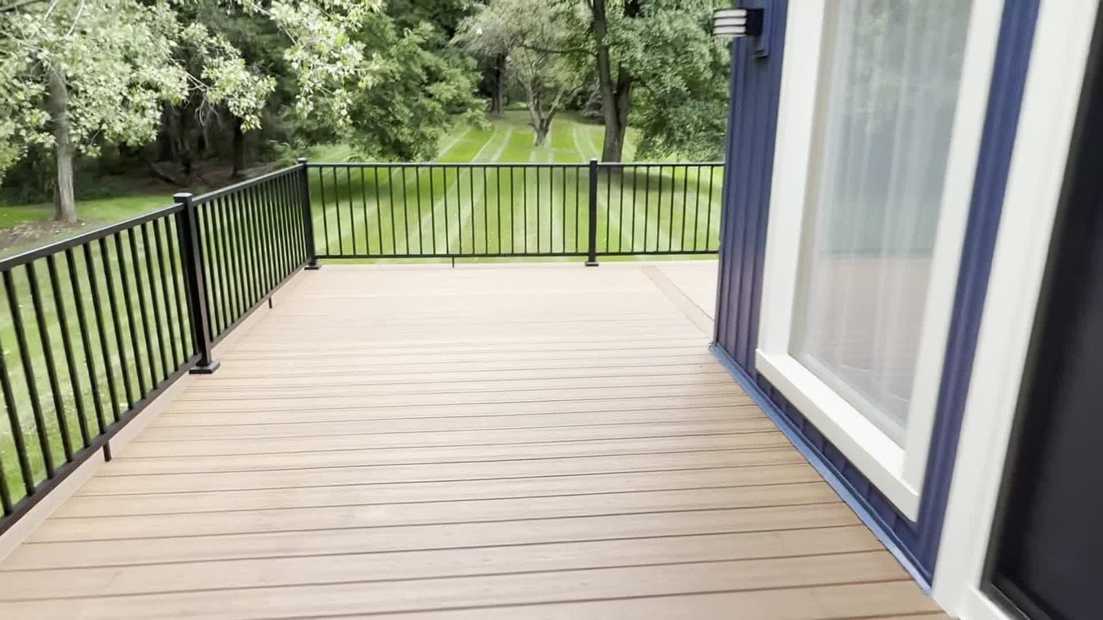 Newly built composite deck with black aluminum railing beside a sliding glass door