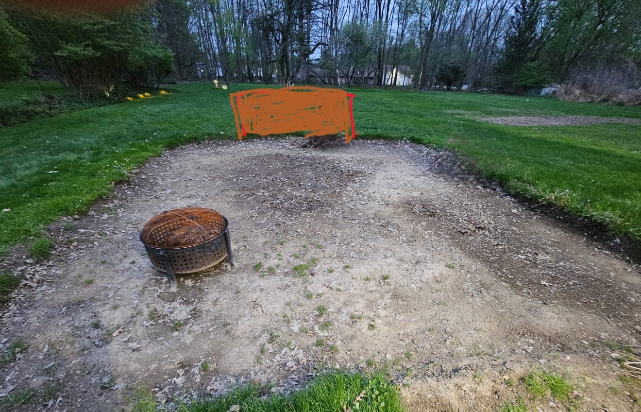 Bare dirt patch with an old fire ring in a backyard